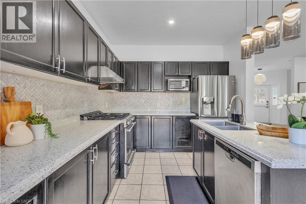 Modern kitchen featuring dark cabinetry, light speckled countertops, and a herringbone tile backsplash - 73 Fitzgerald Drive, Cambridge, ON - Indoor Photo Showing Kitchen With Double Sink With Upgraded Kitchen