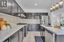 Modern kitchen featuring dark cabinetry, light speckled countertops, and a herringbone tile backsplash -