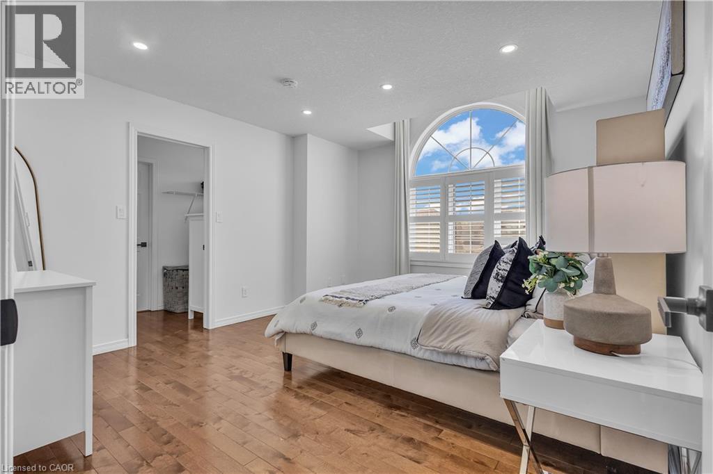 Bedroom featuring a prominent arched window with louvered shutters, recessed lighting, and wood-finish flooring - 73 Fitzgerald Drive, Cambridge, ON - Indoor Photo Showing Bedroom