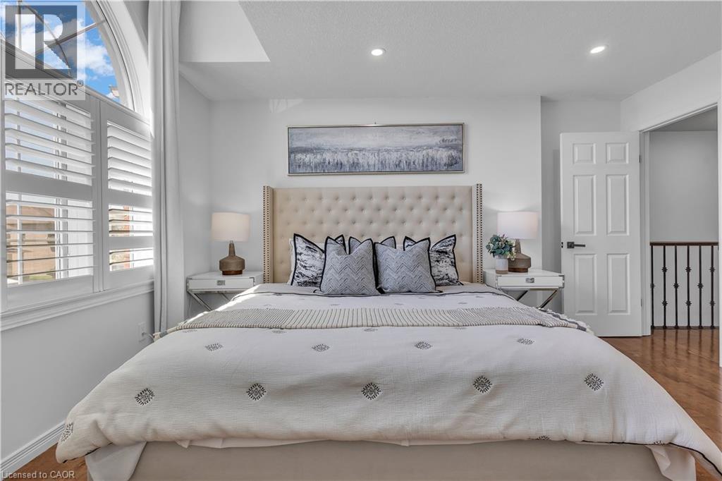 Bedroom featuring an arched window, plantation shutters, recessed lighting, wood-finish flooring, and a six-panel door with matte black hardware - 73 Fitzgerald Drive, Cambridge, ON - Indoor Photo Showing Bedroom