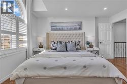 Bedroom featuring an arched window, plantation shutters, recessed lighting, wood-finish flooring, and a six-panel door with matte black hardware -