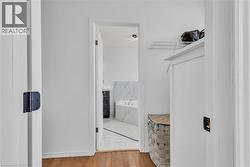 Interior hallway featuring wood-finish flooring transitioning to a bathroom with marble-patterned floor tiles -
