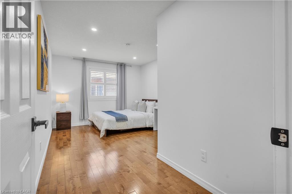 Bedroom featuring wood-finish flooring, recessed lighting, and a window with plantation shutters and drapes - 73 Fitzgerald Drive, Cambridge, ON - Indoor Photo Showing Bedroom
