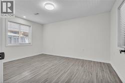Room featuring wood-finish flooring, crisp white walls, and a recessed window with blinds -