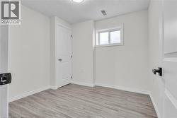 Neutral-toned room featuring light wood-finish flooring, white walls, and a single window -