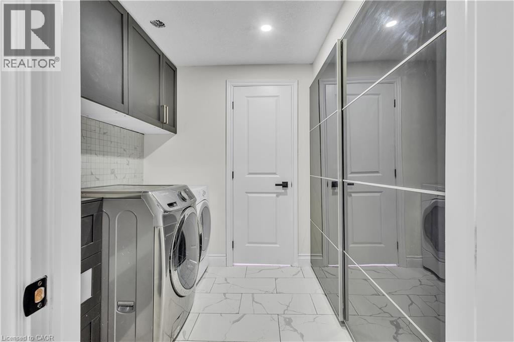 Laundry area featuring a tile backsplash, dark cabinetry, and white flooring - 73 Fitzgerald Drive, Cambridge, ON - Indoor Photo Showing Laundry Room