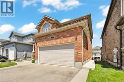 Red brick exterior featuring a light-colored garage door and an arched window on the upper level -