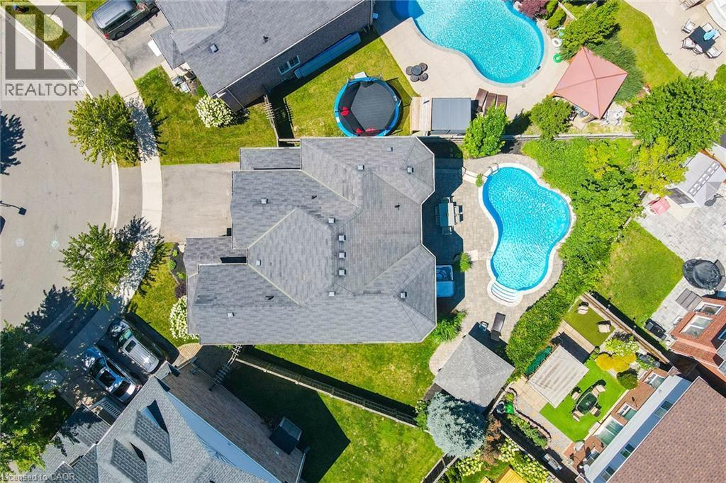 Curved inground pool with surrounding hardscaping and a stone patio - 1533 Morse Place, Milton, ON - Outdoor With In Ground Pool With View