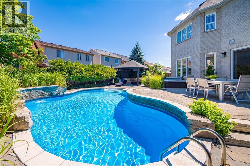 Curved inground pool with integrated stone waterfall feature - 1533 Morse Place, Milton, ON - Outdoor With In Ground Pool With Deck Patio Veranda