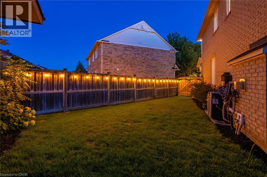 Spacious backyard featuring a manicured lawn, full privacy fencing with string lighting, and mature perimeter landscaping - 1533 Morse Place, Milton, ON - Outdoor