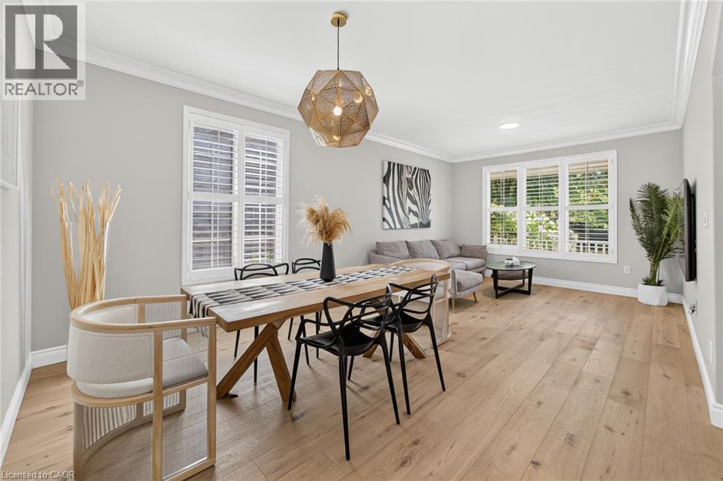 Open-concept living space featuring wide-plank wood-finish flooring, white crown molding, and large windows with plantation shutters - 1533 Morse Place, Milton, ON - Indoor Photo Showing Dining Room