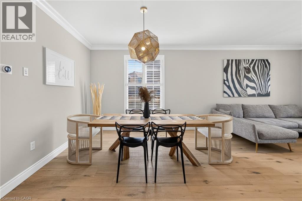 Open-concept living area featuring light wood-finish flooring, crisp white crown molding, and a modern geometric pendant light fixture - 1533 Morse Place, Milton, ON - Indoor Photo Showing Other Room