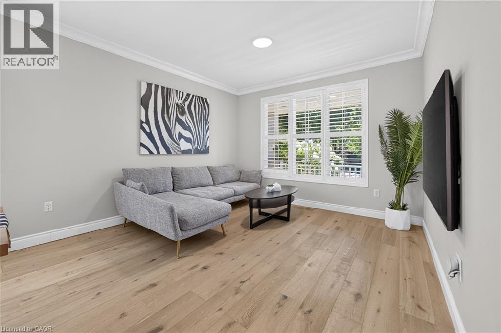 Bright and airy living room showcasing wood-finish flooring, recessed ceiling lighting, and large multi-pane windows with plantation shutters - 1533 Morse Place, Milton, ON - Indoor Photo Showing Living Room