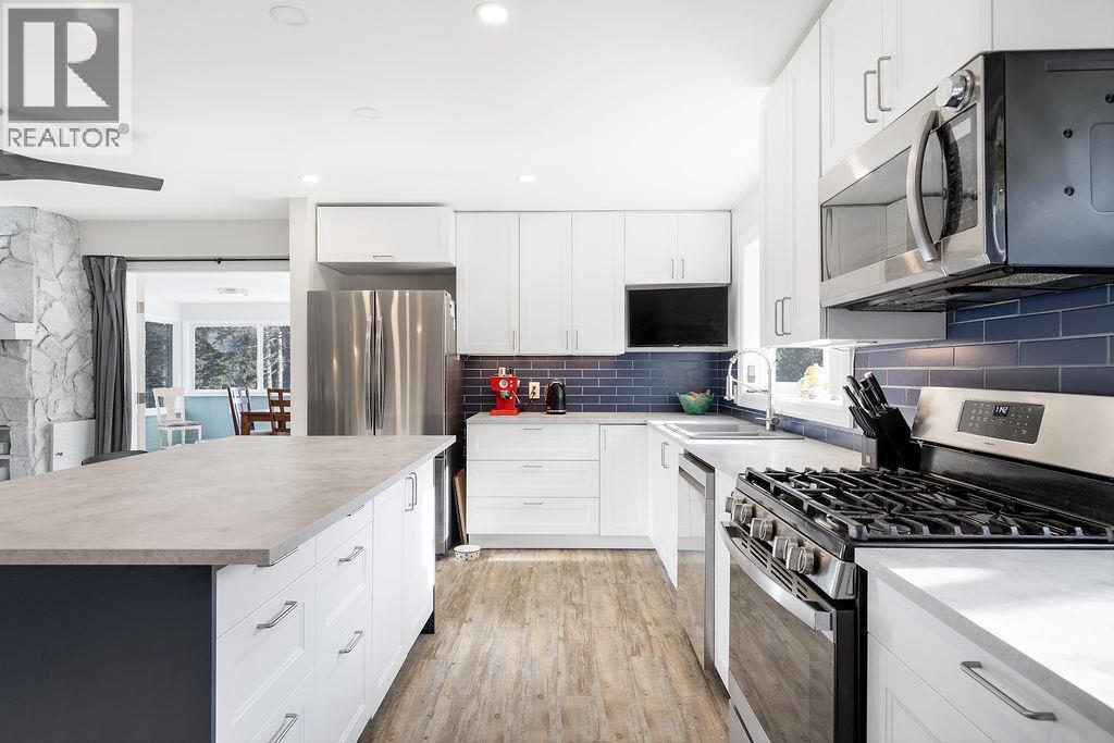 Renovated Kitchen, stainless steal appliances and large island that faces the living room. Views from the front and back of house. - 2527 Islandview Road, Blind Bay, BC - Indoor Photo Showing Kitchen With Double Sink With Upgraded Kitchen