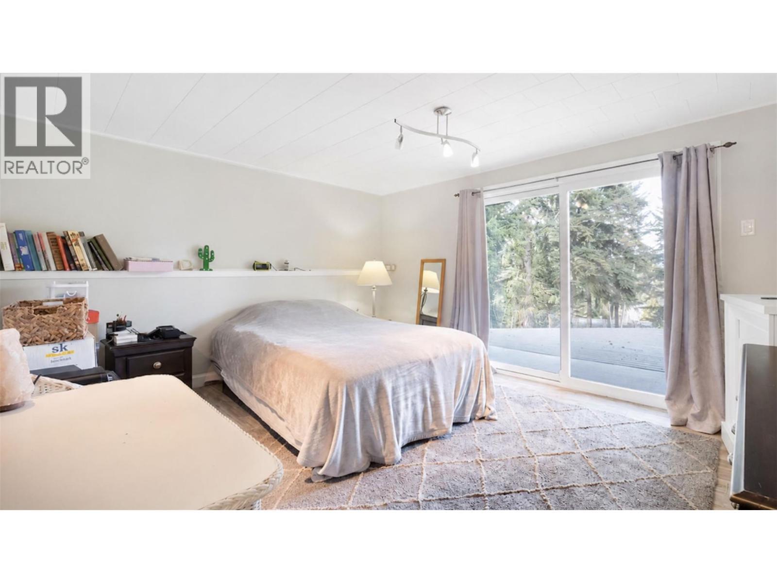 Third bedroom located in basement. Large patio doors open to the lower deck/yard and hot tub access. - 2527 Islandview Road, Blind Bay, BC - Indoor Photo Showing Bedroom