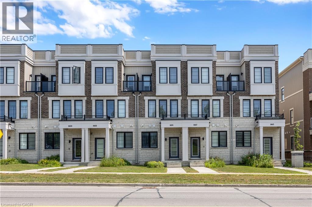 Modern townhome exterior featuring brick and stone cladding, multiple balconies with glass railings, large windows with dark frames, and covered front entrances with architectural columns - 1451 Green Road, Bowmanville, ON - Outdoor With Facade