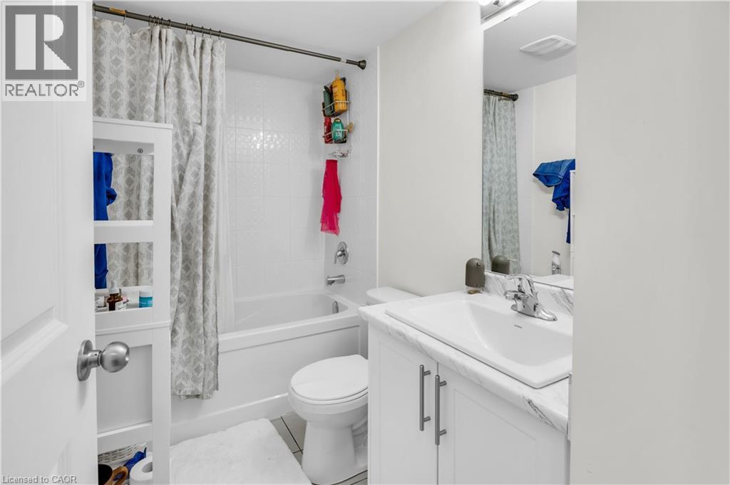 Bathroom featuring a white bathtub with subway-style tile surround, a built-in vanity with a white countertop and integrated sink, and a large wall-mounted mirror - 1451 Green Road, Bowmanville, ON - Indoor Photo Showing Bathroom
