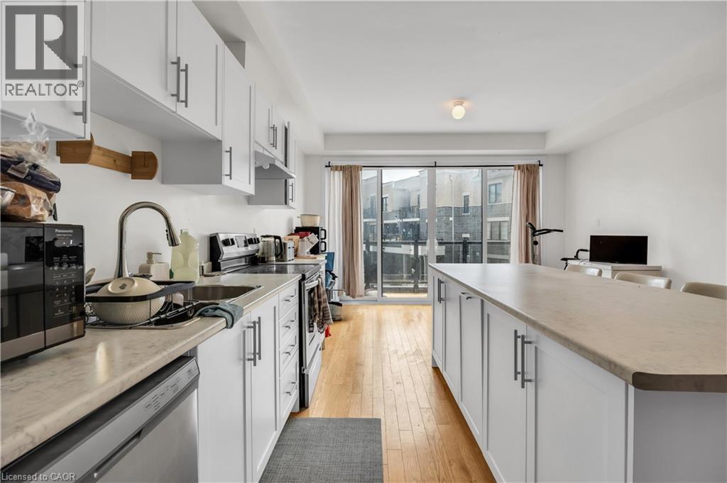 Open-concept kitchen featuring white cabinetry, light-toned countertops, a stainless steel sink with a gooseneck faucet, and light wood-finish flooring - 1451 Green Road, Bowmanville, ON - Indoor Photo Showing Kitchen With Upgraded Kitchen