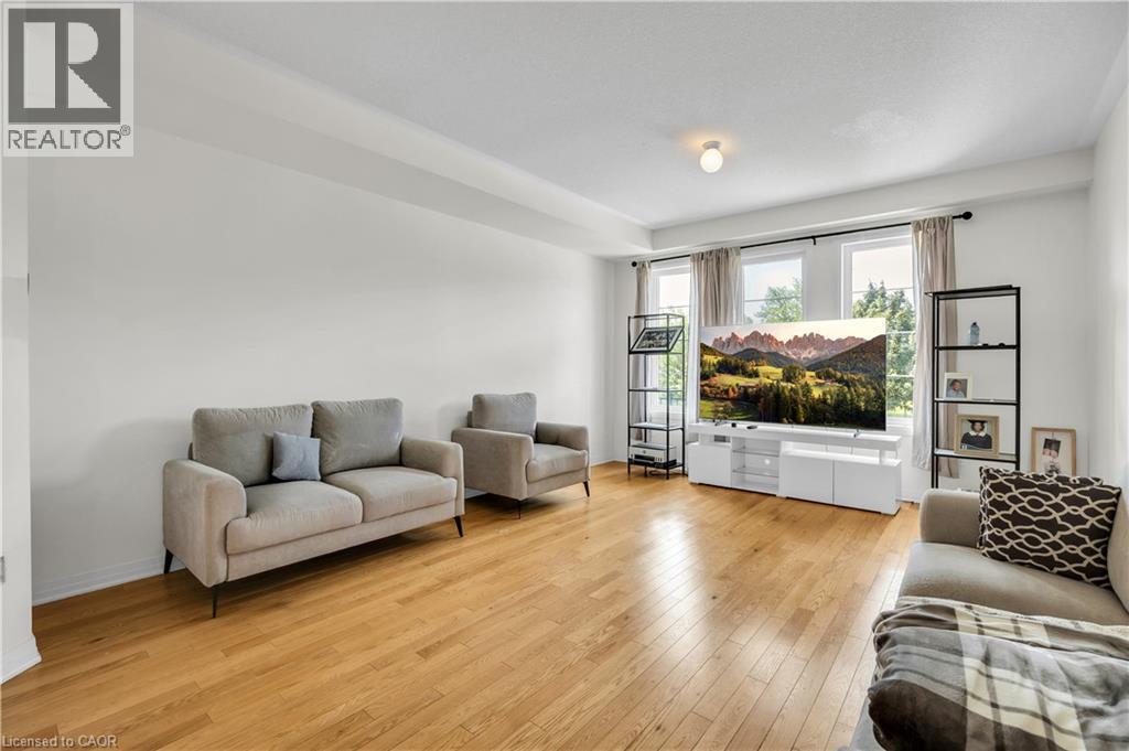 Spacious living area featuring wood-finish flooring, white walls, and multiple windows with curtain rods - 1451 Green Road, Bowmanville, ON - Indoor Photo Showing Living Room