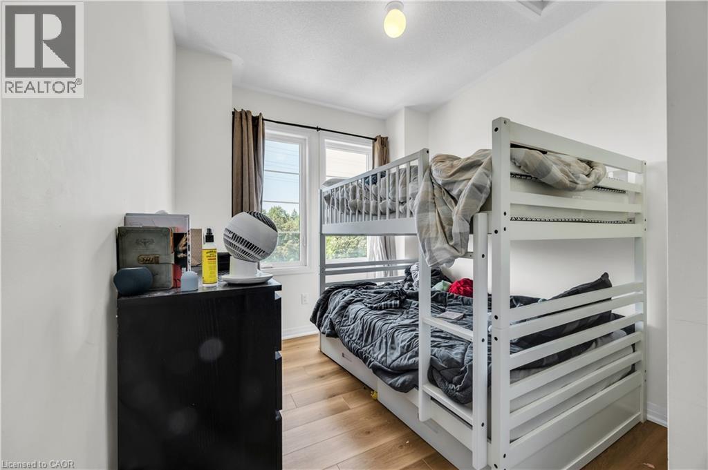 Bright interior room featuring a window with exterior views, wood-finish flooring, white walls, and a ceiling-mounted light fixture - 1451 Green Road, Bowmanville, ON - Indoor Photo Showing Bedroom