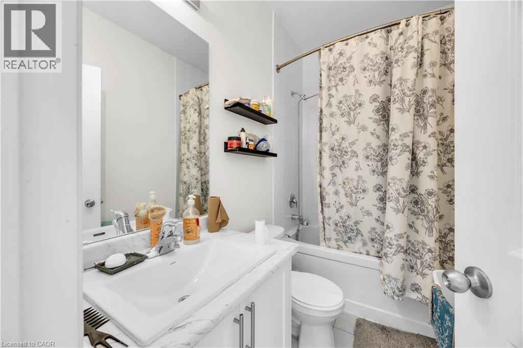 Bathroom featuring a white vanity with an integrated sink, a rectangular mirror, and a white bathtub with a shower fixture - 1451 Green Road, Bowmanville, ON - Indoor Photo Showing Bathroom