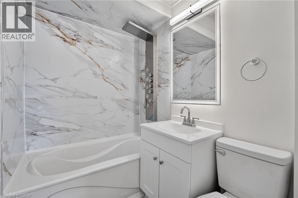 Bathroom featuring a white bathtub with a multi-function shower panel - 36 Mahony Avenue, Hamilton, ON - Indoor Photo Showing Bathroom