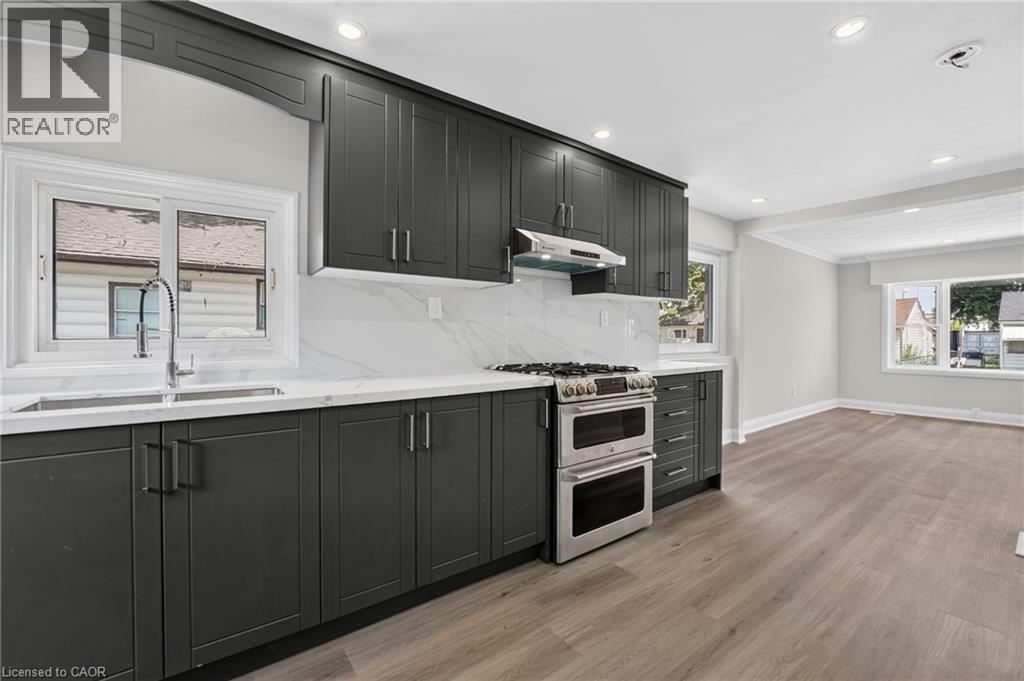 Modern kitchen featuring dark cabinetry, white countertops, and a full tile backsplash - 36 Mahony Avenue, Hamilton, ON - Indoor Photo Showing Kitchen With Double Sink With Upgraded Kitchen
