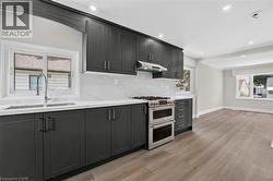 Modern kitchen featuring dark cabinetry, white countertops, and a full tile backsplash -
