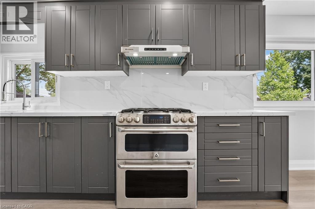 Contemporary kitchen featuring dark gray shaker cabinetry, white countertops, and a white tile backsplash with subtle veining - 36 Mahony Avenue, Hamilton, ON - Indoor Photo Showing Kitchen With Upgraded Kitchen