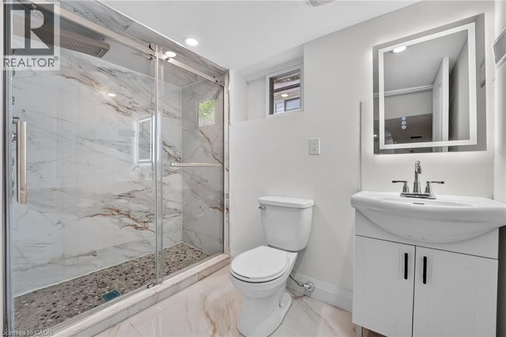 Contemporary bathroom featuring a spacious glass-enclosed shower with marble-patterned tile walls and a pebble-stone floor - 36 Mahony Avenue, Hamilton, ON - Indoor Photo Showing Bathroom