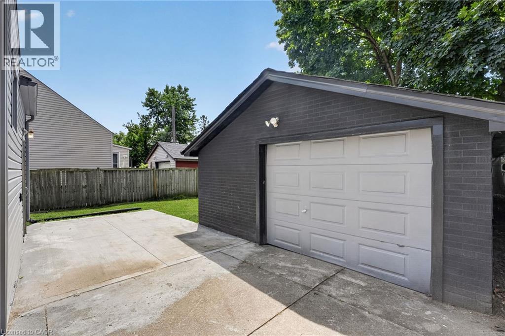 Detached garage featuring a paneled door and dark brick exterior - 36 Mahony Avenue, Hamilton, ON - Outdoor With Exterior