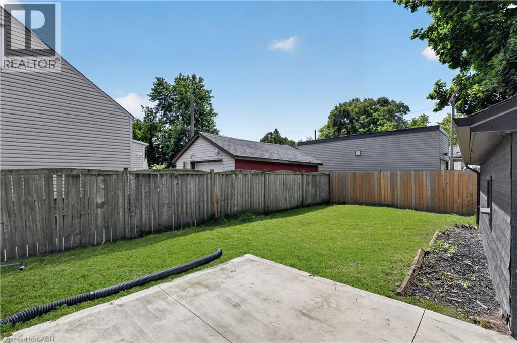 Enclosed backyard featuring a concrete patio, a manicured lawn, and wood privacy fencing - 36 Mahony Avenue, Hamilton, ON - Outdoor