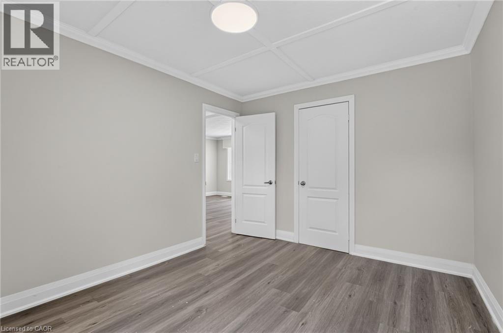 Spacious interior room featuring wood-finish flooring, light gray wall tones, white baseboards, and white crown molding - 36 Mahony Avenue, Hamilton, ON - Indoor Photo Showing Other Room