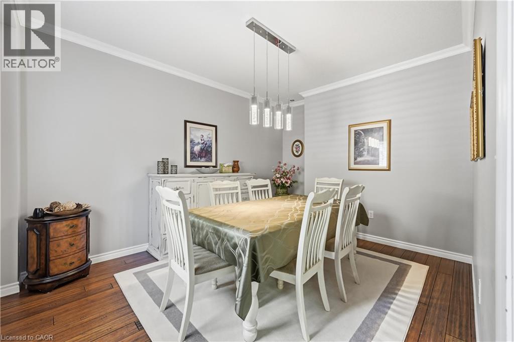 Dining area featuring wood-finish flooring, a contemporary linear pendant light fixture, and crown molding - 10 Kopperfield Lane, Hamilton, ON - Indoor Photo Showing Dining Room