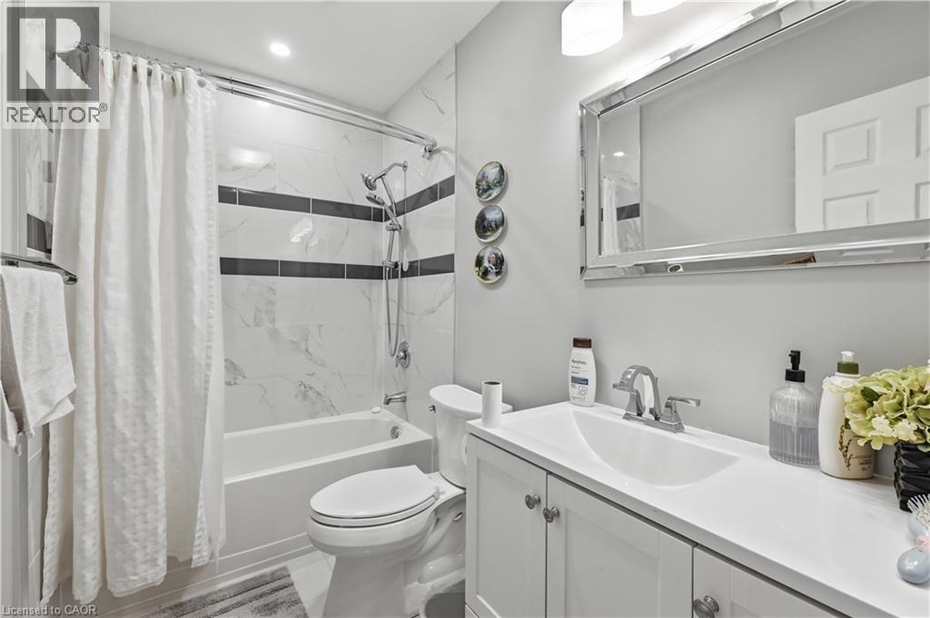 Full bathroom featuring a white vanity with integrated sink, chrome faucet, and framed mirror - 10 Kopperfield Lane, Hamilton, ON - Indoor Photo Showing Bathroom