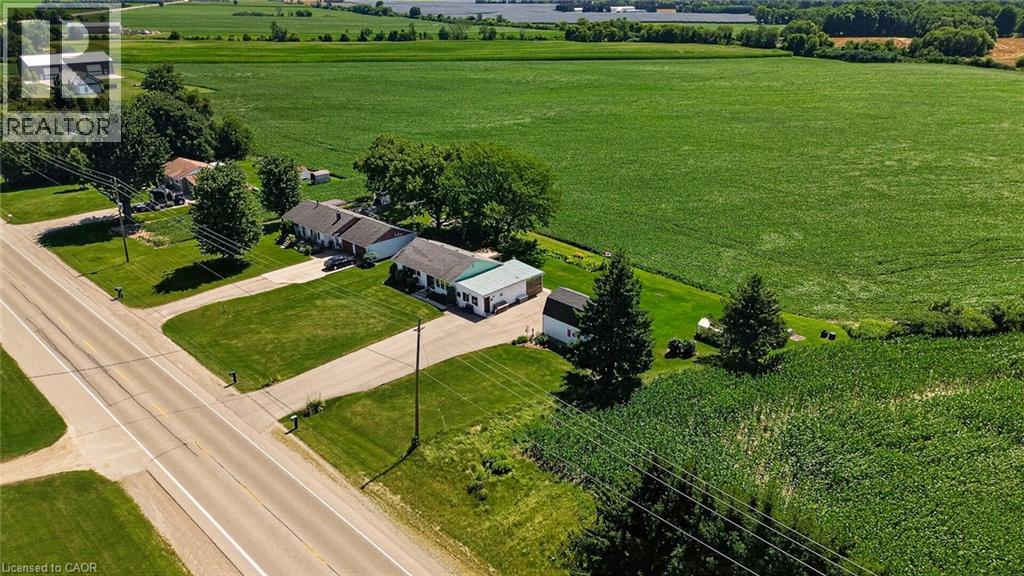 Property with two structures featuring light-colored siding and a green metal roof, set on a manicured lawn - 184726 Cornell Road, Tillsonburg, ON - Outdoor With View