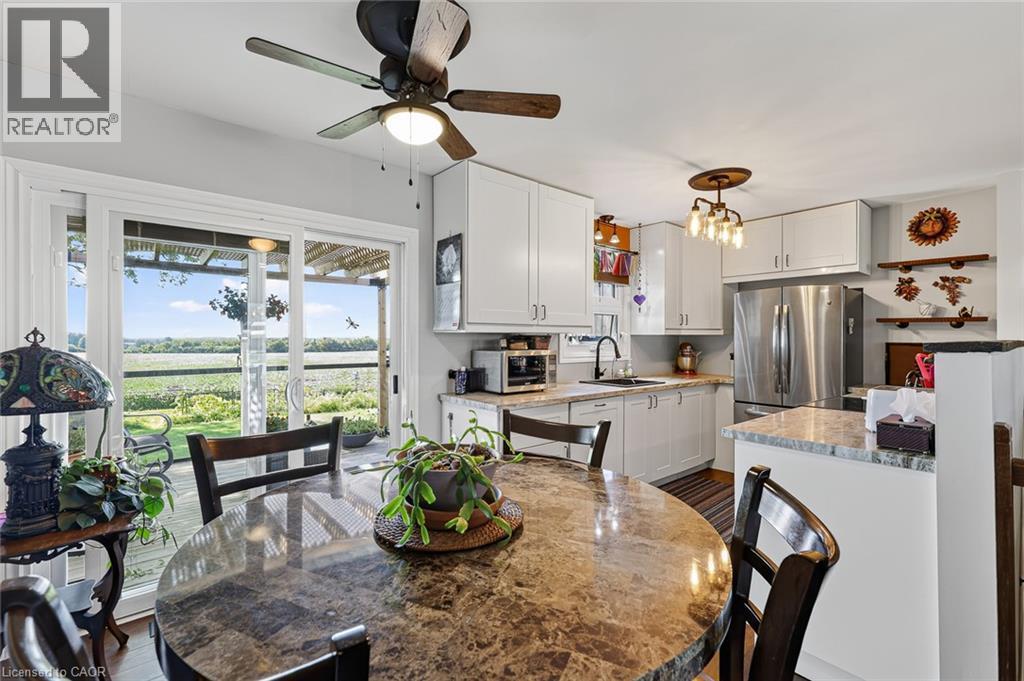 Kitchen with white cabinetry, stainless steel refrigerator, and stone-finish countertops - 184726 Cornell Road, Tillsonburg, ON - Indoor Photo Showing Dining Room