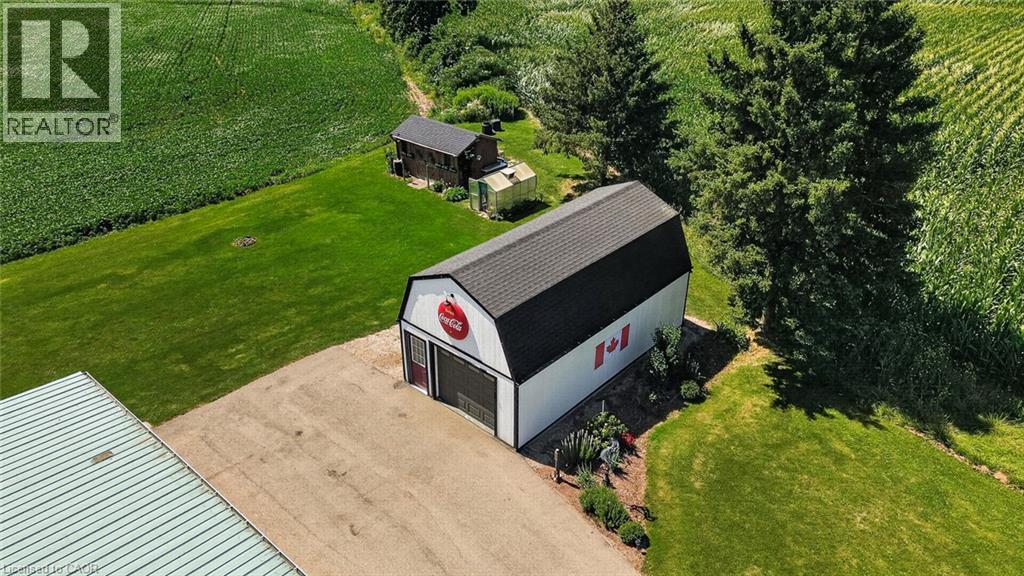 Spacious barn with a black shingled roof, white siding, and a large roll-up door - 184726 Cornell Road, Tillsonburg, ON - Outdoor