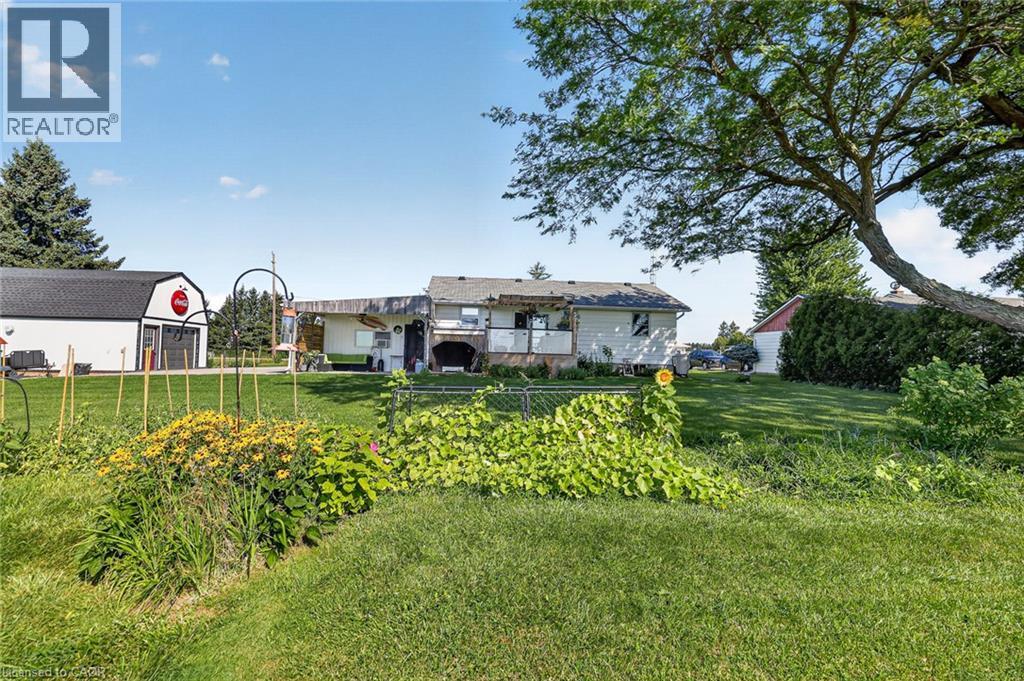 Expansive green lawn with mature trees and established garden beds - 184726 Cornell Road, Tillsonburg, ON - Outdoor
