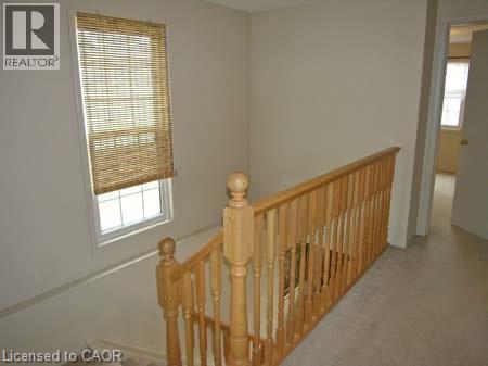 Staircase landing featuring a natural wood railing, balusters, and newel posts - 151 Clairfields Drive E Unit# 39, Guelph, ON - Indoor Photo Showing Other Room