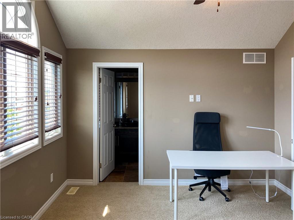 Vaulted ceiling room featuring an arched window, rectangular windows with horizontal blinds, carpet flooring, and a doorway opening to a bathroom with tile flooring - 180 Huck Crescent, Kitchener, ON - Indoor Photo Showing Office