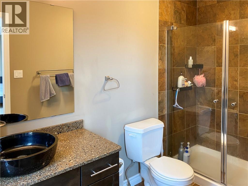 Bathroom featuring a glass-enclosed shower with full-height tile surround, dark wood-finish vanity with a vessel sink, and a speckled countertop - 180 Huck Crescent, Kitchener, ON - Indoor Photo Showing Bathroom
