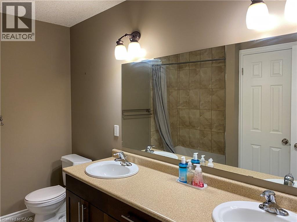 Double vanity with undermount sinks, speckled countertop, and dark wood-finish cabinetry - 180 Huck Crescent, Kitchener, ON - Indoor Photo Showing Bathroom