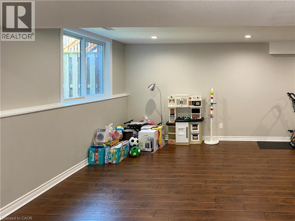 Finished lower level featuring rich wood-finish flooring, recessed lighting, and a white-trimmed window - 180 Huck Crescent, Kitchener, ON - Indoor Photo Showing Other Room