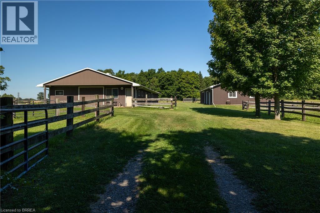 Gravel driveway leading to a brown barn structure with white trim, surrounded by wood fencing and verdant grounds - 269 Brant County Road 22, Ancaster, ON - Outdoor