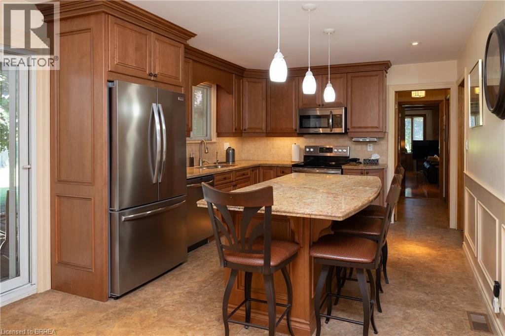 Kitchen featuring wood cabinetry, stainless steel appliances, a stone countertop island, tile flooring, and pendant lighting - 269 Brant County Road 22, Ancaster, ON - Indoor Photo Showing Other Room