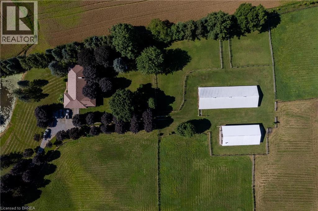 Expansive property featuring a residence with a brown shingled roof, a paved drive, a pond, and two white outbuildings - 269 Brant County Road 22, Ancaster, ON - Outdoor With View