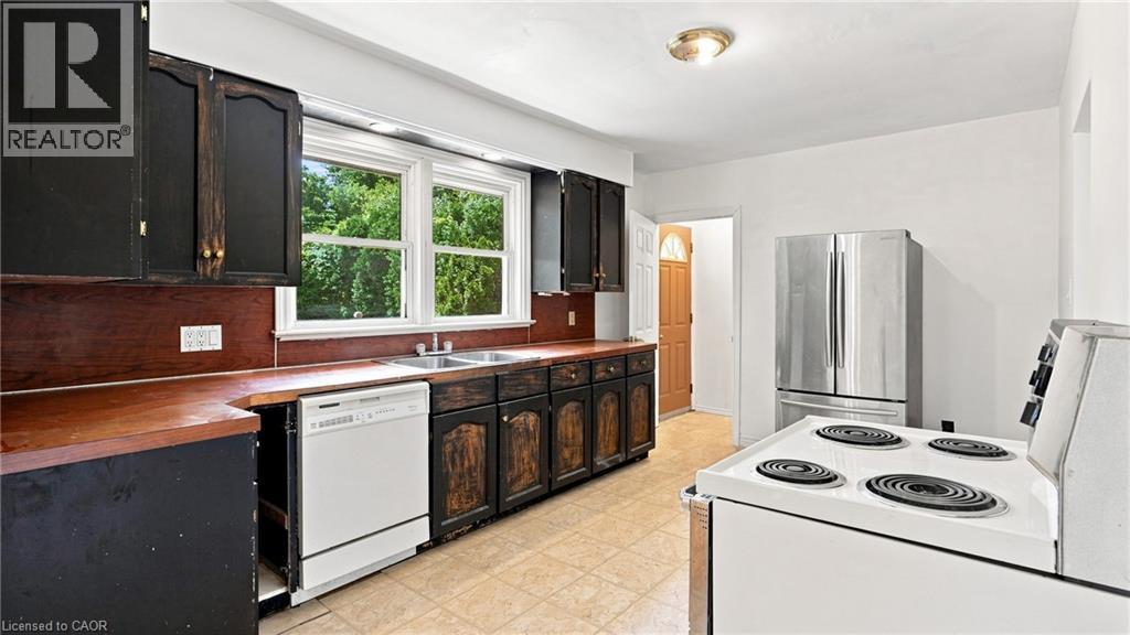 Kitchen featuring wood-finish countertops, black cabinetry, a double-basin sink, and a white dishwasher - 524 Dorval Drive, Ancaster, ON - Indoor Photo Showing Kitchen With Double Sink