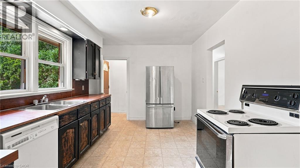 Kitchen featuring a dual basin stainless steel sink, wood-finish countertops, dark cabinetry, and a white electric range - 524 Dorval Drive, Ancaster, ON - Indoor Photo Showing Kitchen With Double Sink