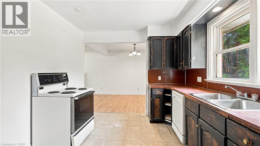 Kitchen featuring dark wood cabinetry, a white electric range, a double basin stainless steel sink, and a dishwasher - 524 Dorval Drive, Ancaster, ON - Indoor Photo Showing Kitchen With Double Sink